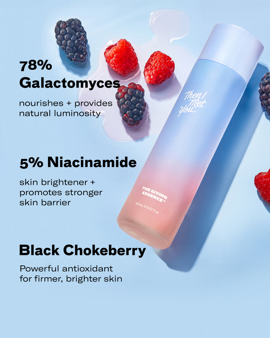 The Giving Essence serum bottle with gradient blue to peach color, surrounded by blackberries and raspberries on a soft blue .