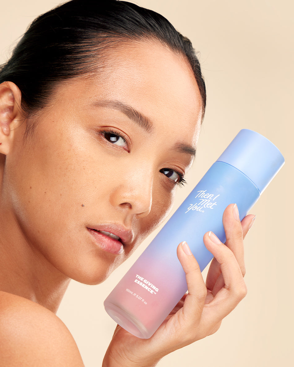 Woman holding pink and blue ombre skincare bottle labeled The Skin Balancing Duo against beige background.