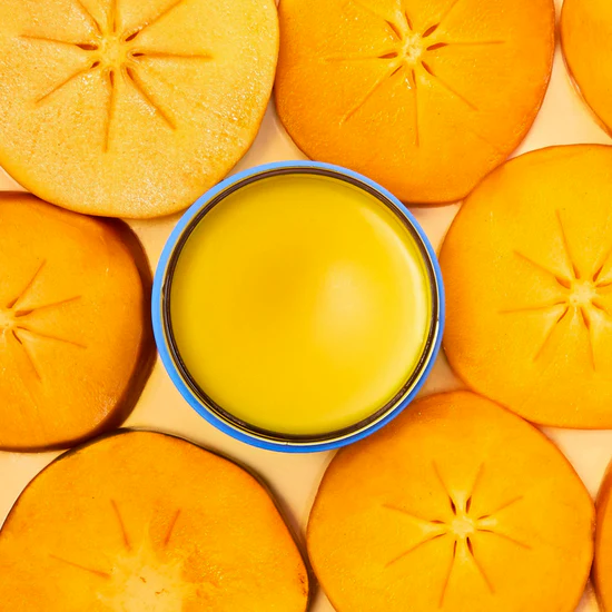 Top view of sliced persimmons with a small container of yellow cream in the center.